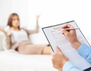 Psychological consultation Professional psychiatrist consulting her patient and making notes in application form