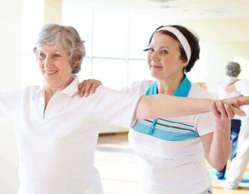 Support Portrait of sporty female supporting her friend while doing physical exercise in sport gym