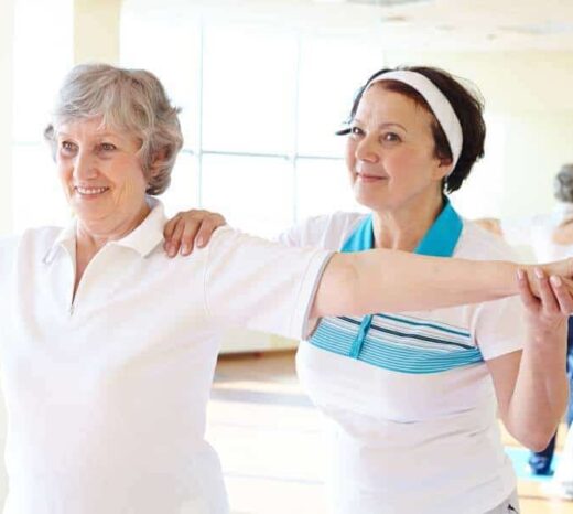 Portrait of sporty female supporting her friend while doing physical exercise in sport gym